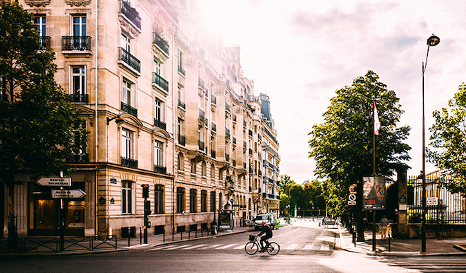 a man cycling across an intersection in the streets of Paris