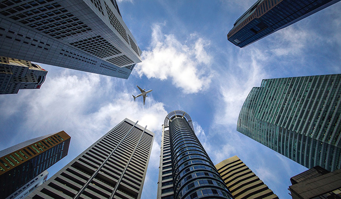 an upward view of an airplane between skyscrapers in Singapore