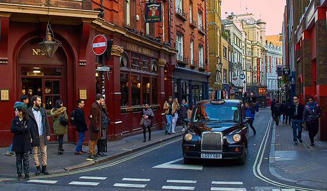 busy Soho with a black cab and people in the street; photo by Pedro Szekely (flickr:@pedrosz)