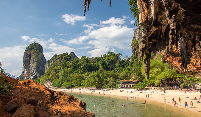 a sunny beach view in Thailand framed with rocky outcrops