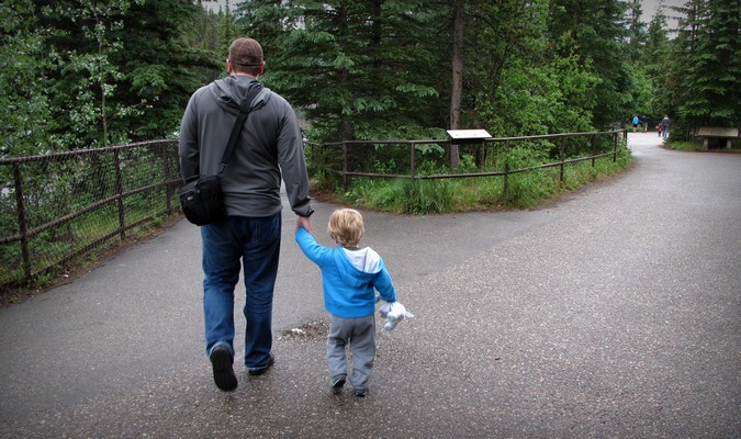Dad and toddler walking through a park on vacation