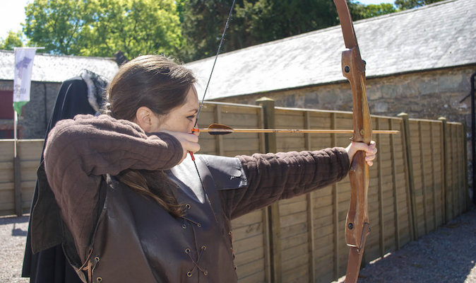 Girl using a bow and arrow to practice archery overseas