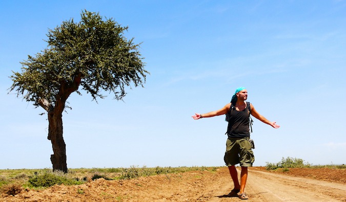 Tomislav, travel blogger stands next to a lone tree in Tanzania Africa