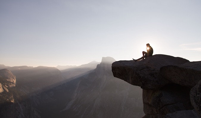 man sitting on a mountain while traveling