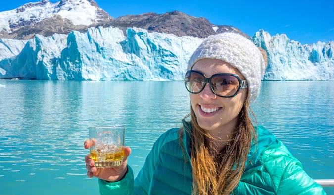 Solo female traveler Kristin Addis posing with a drink near the O’Higgins Glacier in Patagonia