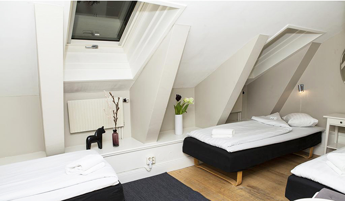 Twin beds in room with slanted ceilings at Lilla Brunn hostel in Stockholm