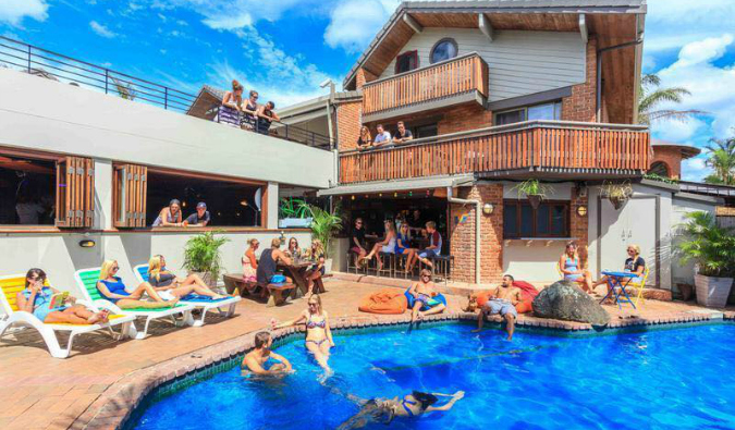 People swimming in and lounging by the pool at Aquarius Backpackers in Byron Bay, Australia.