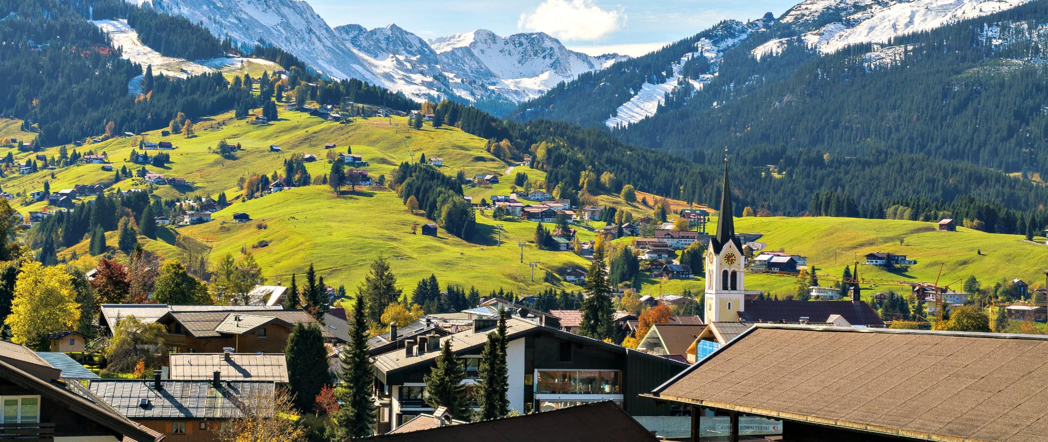 a traditional Austrian home overlooking the snow capped mountains and rolling hills in the Austria countryside