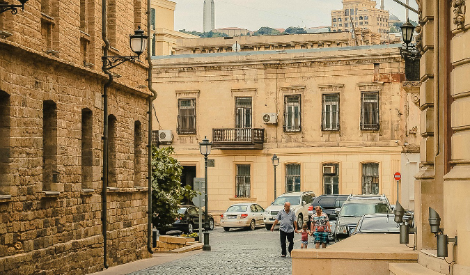 locals out for a walk in Baku, Azerbaijan with old, gritty buildings all around them