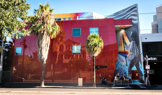 Exterior of Base St. Kilda hostel, now Nomads, in Australia, a red building with a colorful mural