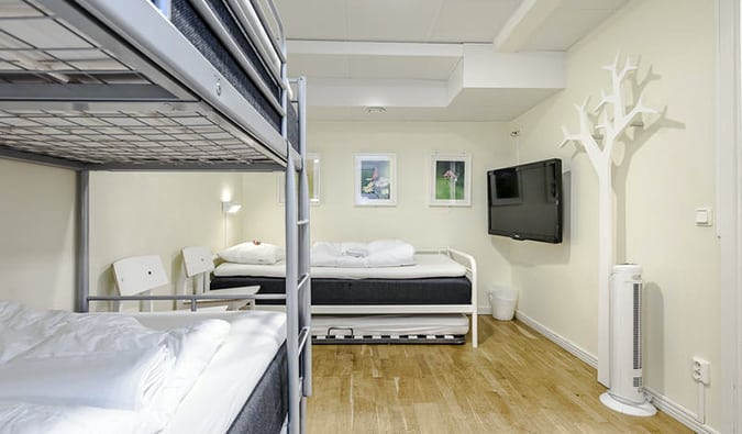 White, minimally decorated room with bunk beds and double bed at City Hostel, Stockholm