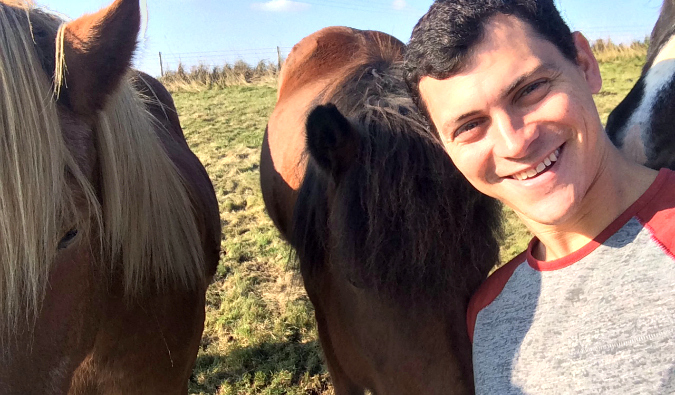 Matt Kepnes, aka Nomadic Matt, hanging out with Icelandic horses in a field in Iceland