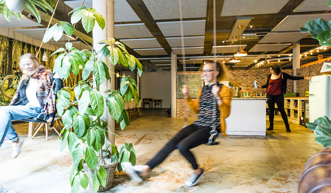 People swinging on swings inside at Ecomama Amsterdam