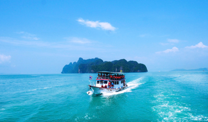 a small shuttle boat in Thailand speeding away from a small island.