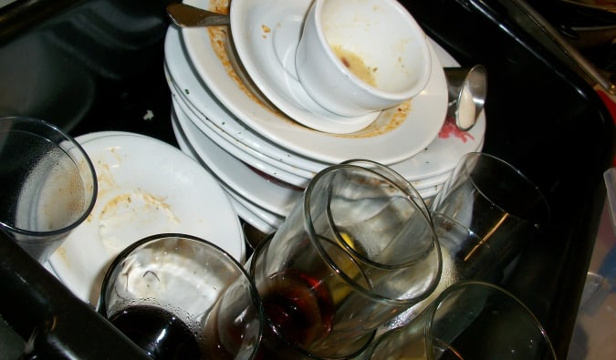 A stack of dirty dishes on a hostel sink