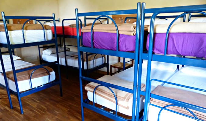 A hostel dorm room full of creaky blue metal bunk beds