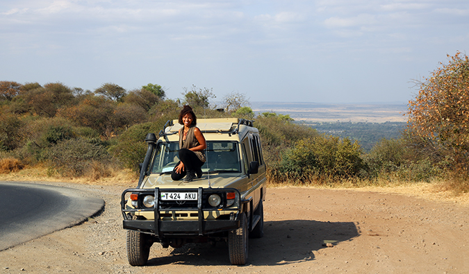 Heather, a solo female travelers, posing on her safari jeep in Africa