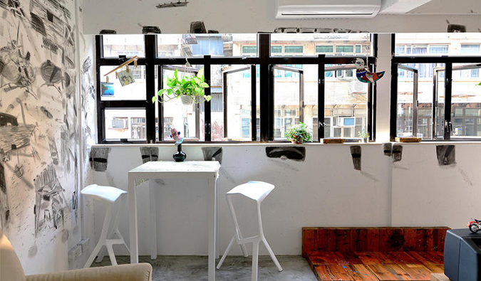 Common area with high table and chairs along wall of windows at Hop Inn, Hong Kong