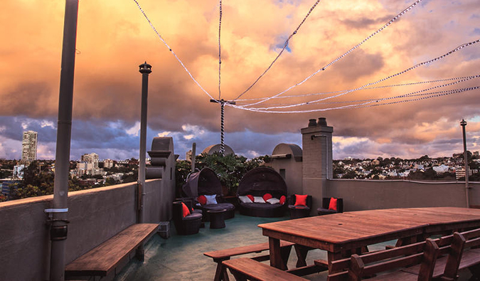 Rooftop terrace with picnic tables at sunset at Kings Cross Backpackers in Sydney, Australia