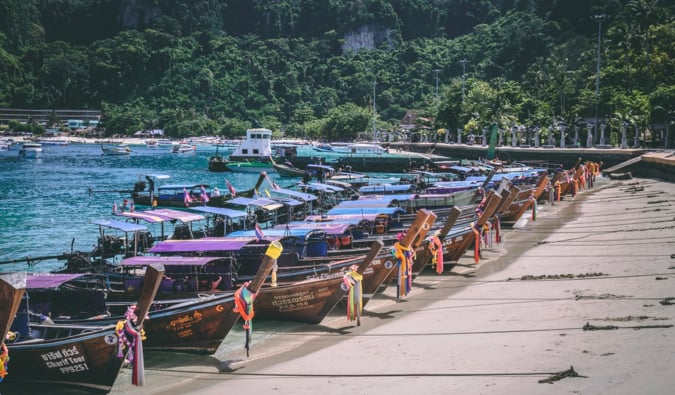 a crowded beach full of boats on Koh Phi Phi in Thailand