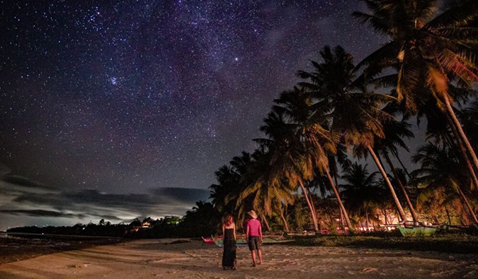 Kristin, a solo female traveler, hanging out with a local on a beach abroad