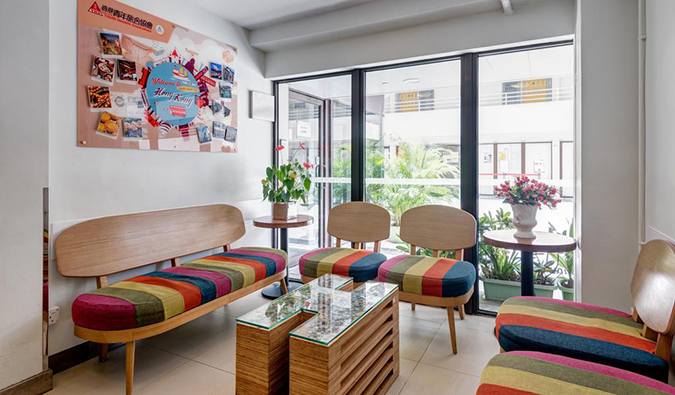Small common room with brightly colored couches and sliding doors leading to courtyard filled with plants at Mei Ho House, Hong Kong