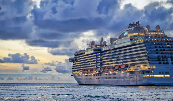 A large cruise ship sailing into a cloudy sunset