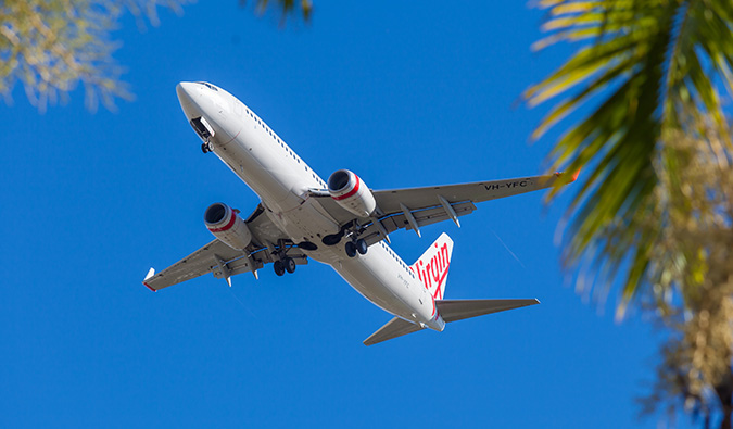 A Virgin Australia airplane flying against a bright blue sky