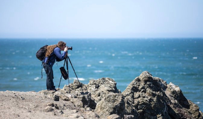Photographer Laurence Norah and his gear set up near the ocean to take pictures