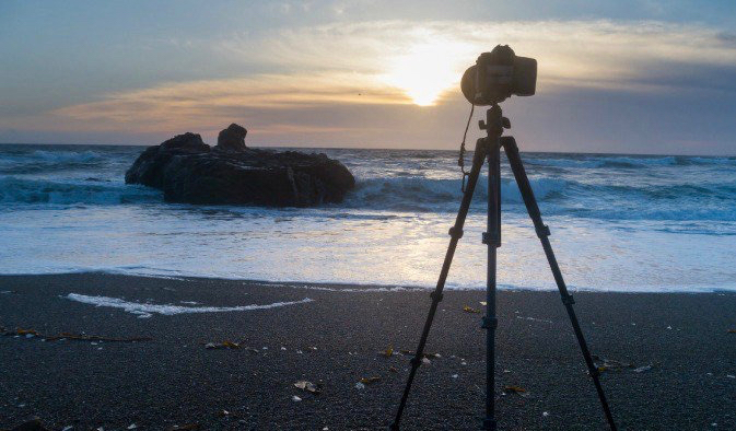 Tripod and camera set up on a natural beach overseas during a relaxing sunset