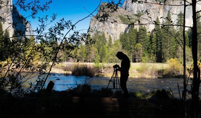 Professional photographer getting ready to shoot a nature travel photo with a blue sky