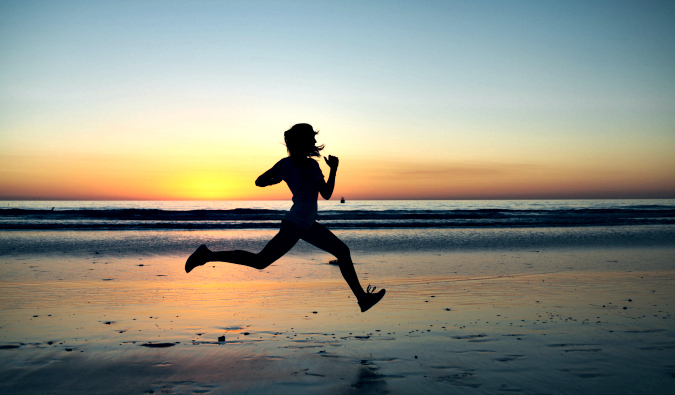 A lone runner sprinting on a beach at sunset