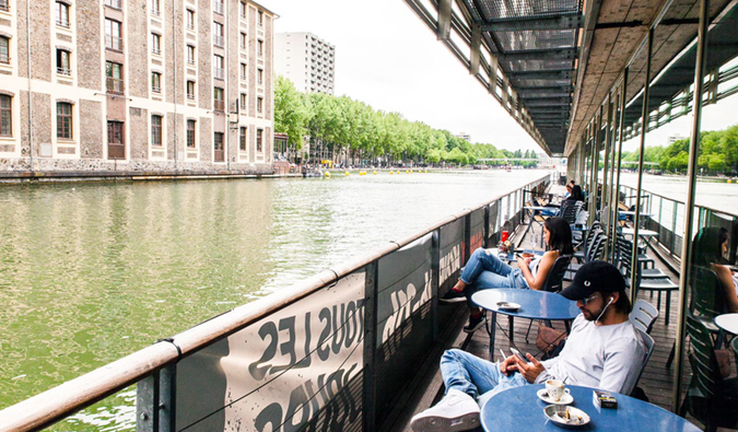 people sitting at the outdoor terrace along the water at St. Christopher’s Canal hostel