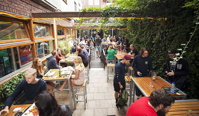 Beer garden filled with people sitting, talking, and drinking at St. Christopher’s at The Winston