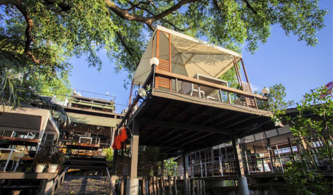 View from the ground looking up at rooms on metal stilts at Tree House hostel in Bangkok.