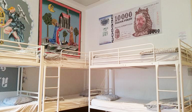 Bunk beds in dorm room with Hungarian paintings on the walls at Vitae Hostel, Budapest