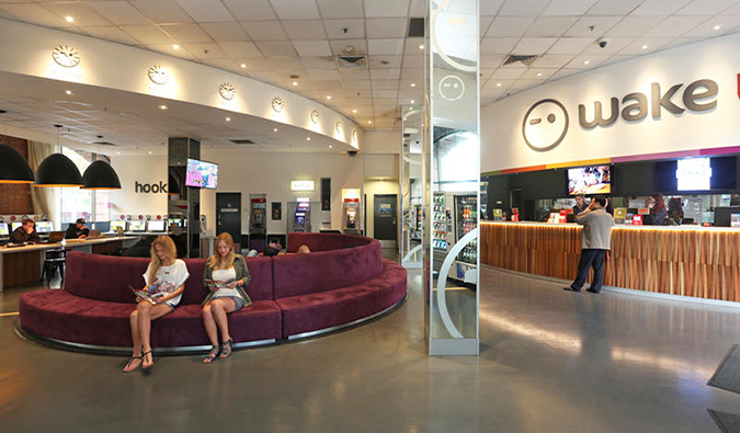 Large lobby with front desk and people sitting on circular couches at Wake Up! Sydney hostel in Australia