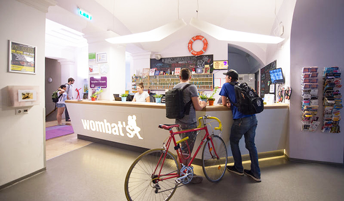 Two people, one with a bicycle, checking into front desk at Wombats Hostel, Budapest