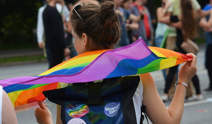 woman with a pride flag flowing out from behind her