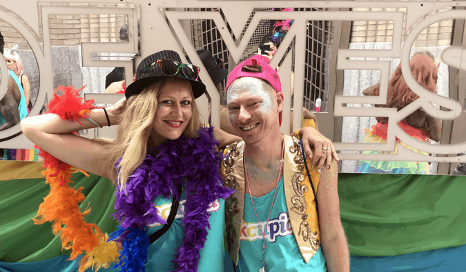 Dani and Adam pose in front of a gay pride parade float in New York City