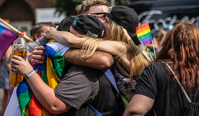 women hugging in the middle of a pride parade