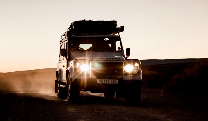 A safari tour jeep driving on a dusty road in Africa