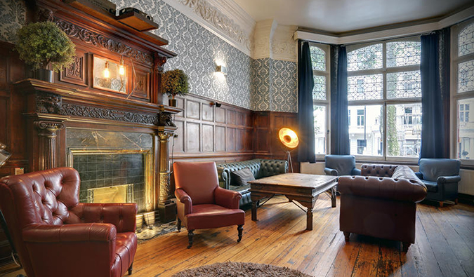 Common room with leather couches and ornately carved wooden fireplace at Astor Hyde Park, London