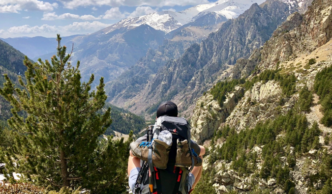 坐在山的预算背包徒步旅行者调查距离