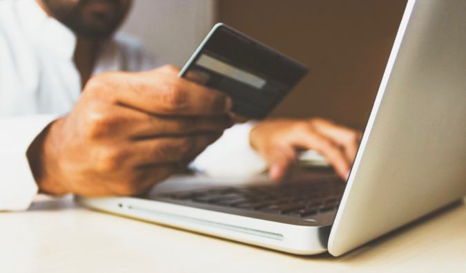 travel credit card being used to shop online by a man at a laptop
