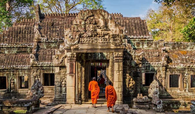 Two monks in orange robes walking in a temple in Cambodia