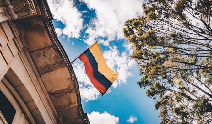 The flag of Colombia blowing in the wid as it hangs from a building