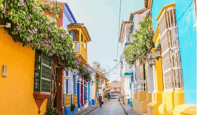 Brightly painted houses with hanging flower gardens lining a narrow street in Cartagena, Colombia