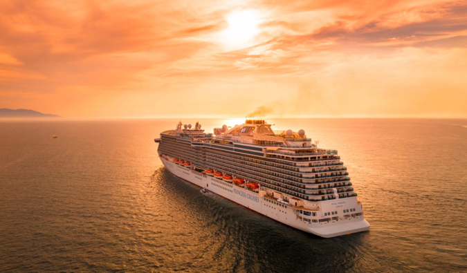 A huge cruise ship sailing into the sunset on calm waters