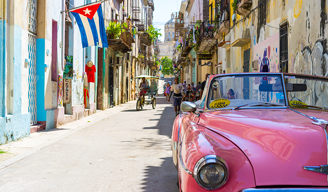 a classic pink car in Cuba on a busy street